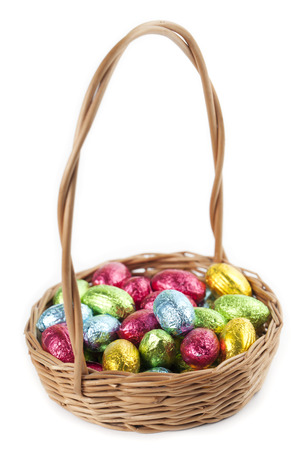 Colorful chocolate Easter eggs in a basket isolated on white の写真素材