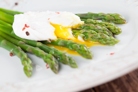Green asparagus with poached egg on a plateの写真素材
