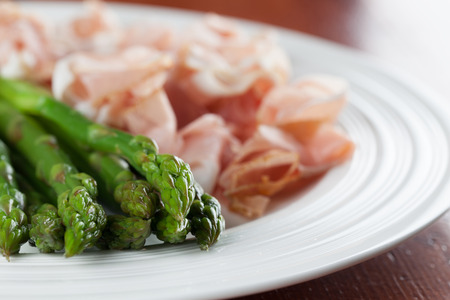 Green asparagus and prosciutto on a plateの写真素材