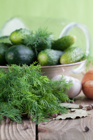 Bowl with fresh cucumbers, dill, garlic, onion, bay leaf and allspice â ingredients for pickle makingの写真素材