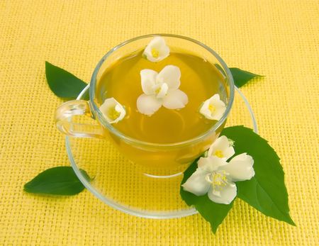 Transparent teacup with tea and flower of jasminの写真素材