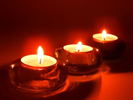 Three aromatic candles in glass candlesticks at nightの写真素材