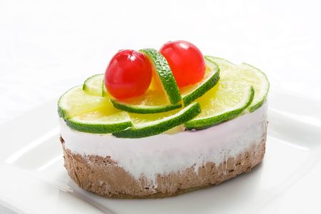 Sponge cake with whipped cream and slices of lime and cherryの写真素材