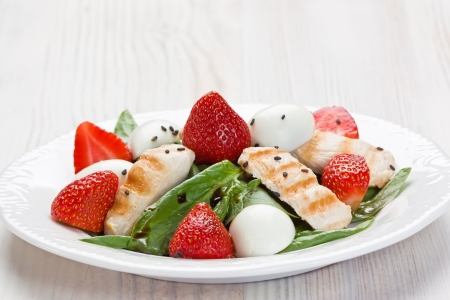 Spinach, grilled chicken, strawberry, and quail eggs salad with balsamic vinegar on white plate の写真素材