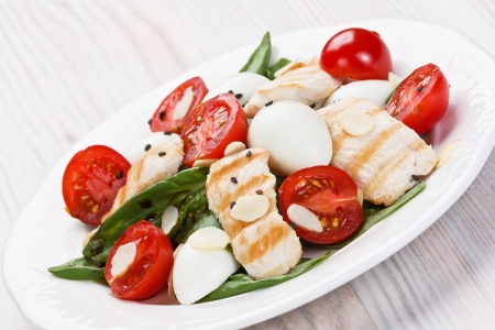 Spinach, grilled chicken, cherry tomatoes, and quail eggs salad with almond chips and balsamic vinegar の写真素材