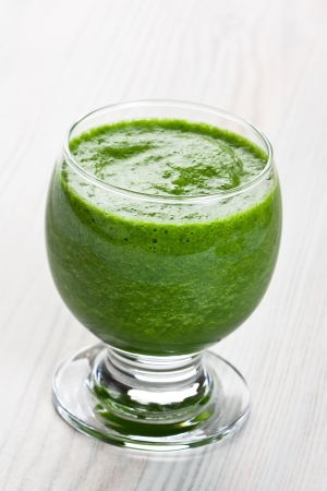Green spinach smoothie vegetable cocktail in glass on wooden backgroundの写真素材