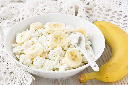 Fresh cottage cheese with banana in white bowlの写真素材