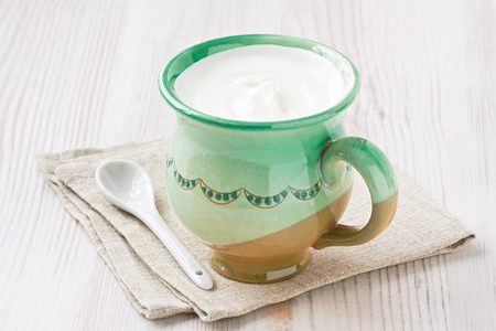 Cup fresh homemade sour cream on wooden background の写真素材