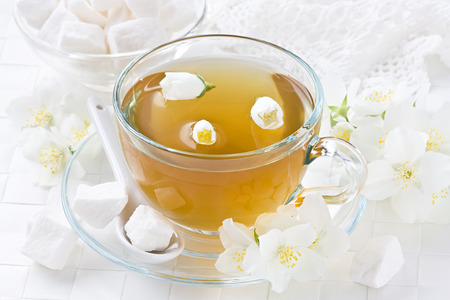 Transparent cup jasmin tea with lump sugar and jasmine flowerの写真素材