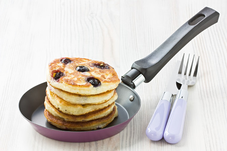 Blueberry pancakes in frying pan on wooden tableの写真素材