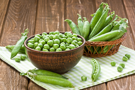 Green peas in ceramic bowl on wooden backgroundの写真素材