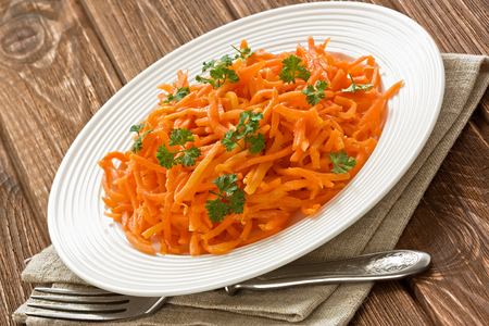 Carrot salad with parsley leaves on rustic wooden backgroundの写真素材
