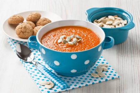 Pumpkin soup with seeds and cookies in blue bowl on wooden backgroundの写真素材