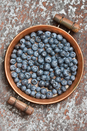 Blueberries on rustic copper tray and rusty metal backgroundの写真素材