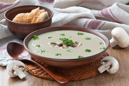 Creamy mushroom soup with fried mushrooms and parsley in bowl on wooden background
の写真素材