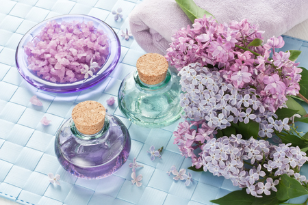 Aromatherapy essential oil in glass bottle, sea salt, towel and lilac flower for SPAの写真素材