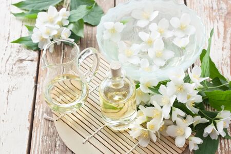 Aromatherapy essential jasmine oil in glass bottle and floating jasmine flower for SPA on wooden backgroundの写真素材