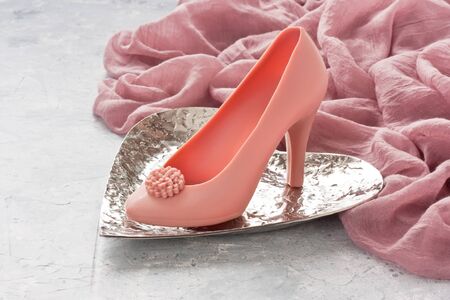 Chocolate woman shoe shape cake in heart form metal plate and pink shawl voile fabric for greeting card on gray rustic concrete background
の写真素材