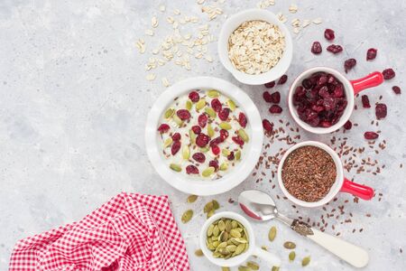 Oatmeal porridge with flaxseeds, dried cranberries and pumpkin seeds for healthy breakfast on gray concrete background 
の写真素材
