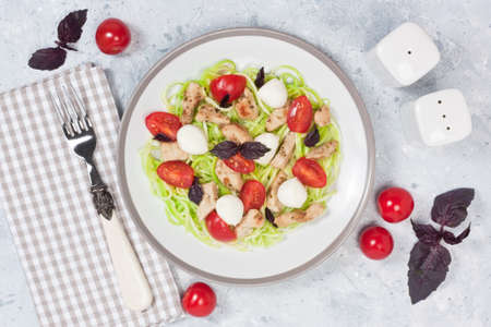 Healthy breakfast with zucchini spaghetti, chicken, mozzarella and cherry tomatoes on gray concrete backgroundの写真素材