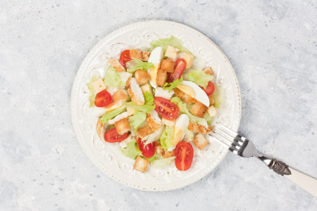 Chicken Caesar salad with lettuce, egg, cherry tomato, parmesan cheese, crouton in plate on gray concrete backgroundの写真素材