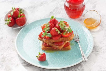 French toasts with strawberry, honey, cinnamon and mint for breakfast in blue plate on gray concrete backgroundの写真素材