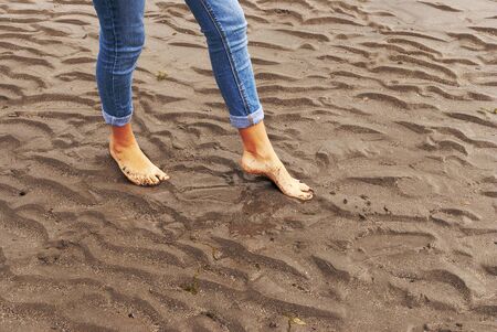 Young woman walking and playing on sandy beach and leaving footprints in the beach. Killbrittain, Kilbrittain beach, Ireland.の写真素材