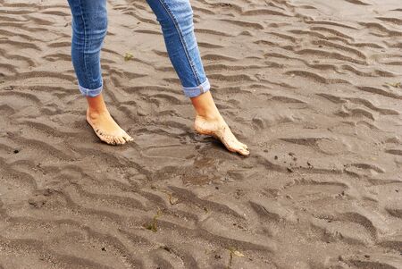 Young woman walking and playing on sandy beach and leaving footprints in the beach. Killbrittain, Kilbrittain beach, Ireland.の写真素材