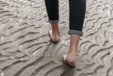 Young woman walking and playing on sandy beach and leaving footprints in the beach. Killbrittain,...