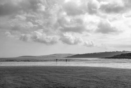 Couple walking on sandy beach leaving footprints in the sand. One father and his daughter enjoying the day. Cloudy day.の写真素材