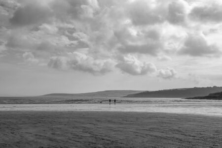 Couple walking on sandy beach leaving footprints in the sand. One father and his daughter enjoying the day. Cloudy day.の写真素材