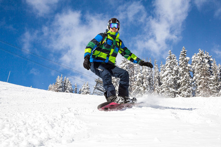 Young man with a snowboard going down the mountain in French Alps.の写真素材