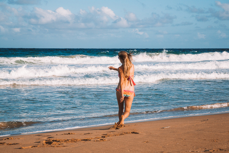Young girl running down the beach in a swimming suite on the island of Kauaiの写真素材