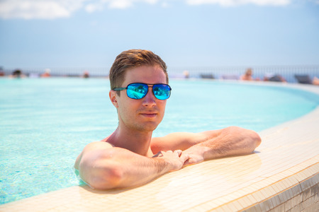 Young man swimming in the infinity pool in a luxury resort.