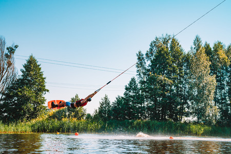 Marupe, Latvia. July 20, 2018. Young man wakeboarding on a lake, making raley, frontroll and jumping the kickers and sliders. Wakeboard.のeditorial素材