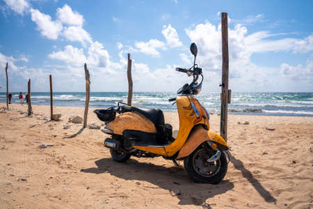 Yellow designed scooter parked on sand at beach on a sunny dayのeditorial素材