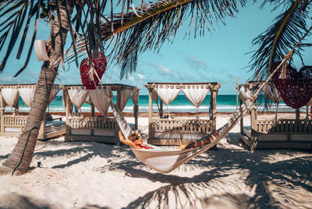 Woman relaxing in hammock at beautiful beach resort with hanging heartsのeditorial素材