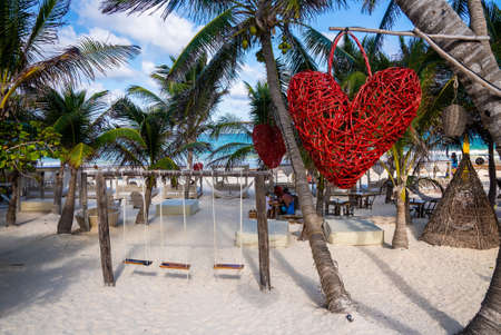 Empty swing and heart shape artwork hanging on tree at beach resortのeditorial素材