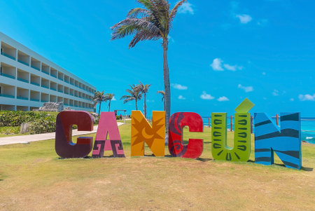 Cancun name sign at park against tree and sea by hotelのeditorial素材