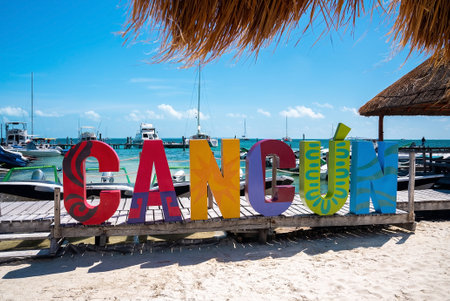 Colorful cancun name sign with pier and moored nautical vessels on seaのeditorial素材
