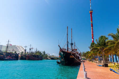 Pirate ships moored on harbor by hotel buildings and tower against skyのeditorial素材