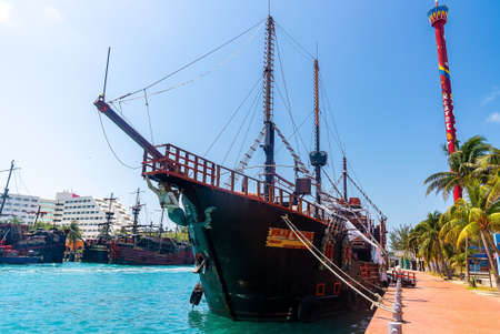 Pirate ships moored on harbor by hotel buildings and tower against skyのeditorial素材