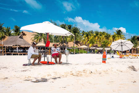 Men and women sunbathing under canopy at beach during summerのeditorial素材