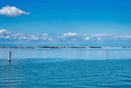 Panorama of sea water surface with wooden post along with city buildngs in the backgroundの写真素材
