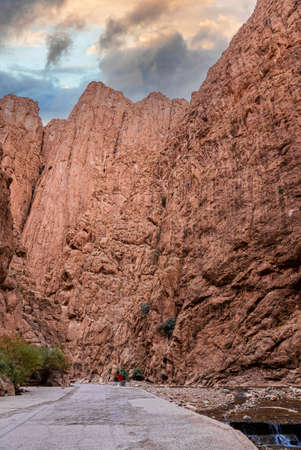 Scenic view of empty road along river through rocky mountainsの写真素材