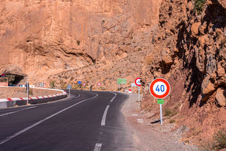 Asphalt road with markings and speed limit signs through mountain