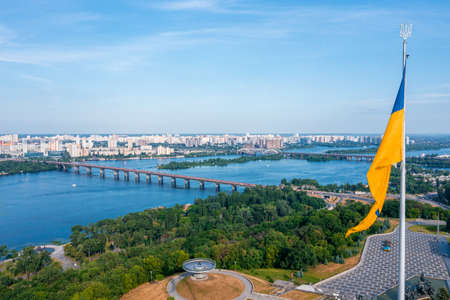 Aerial view of the Ukrainian flag waving in the wind against the city of Kyivの写真素材