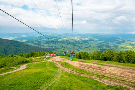 Beautiful view of ski lifts over grassy covered hill with green rural landscape