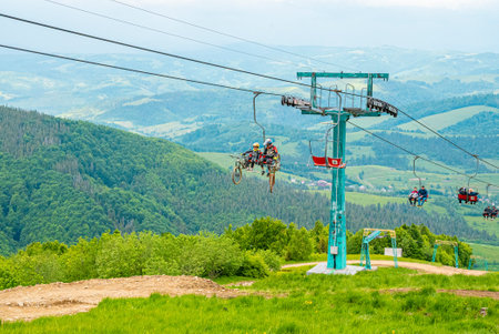 People using chair lifts over grassy covered hill against beautiful landscape