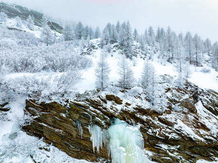 Large ice stalactites hang from the high cliff